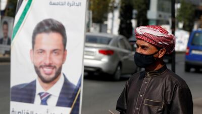 A man wearing a face mask walks past a poster of one of the candidates, ahead of parliamentary elections which will be held on November 10, amid fears over rising number of the coronavirus disease cases, in Amman, Jordan. Reuters
