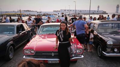 A woman poses for a picture in front of a 1966 Ford Thunderbird.