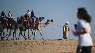 Tourists ride camels during the seventh annual Pyramids Half Marathon at the Pyramids of Giza