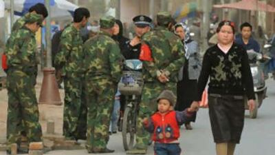 Northwest attacks: An Uighur woman walks with her son past security forces in the town of Kashgar, Xinjiang Province.