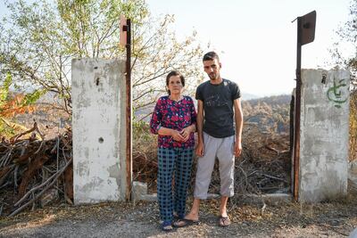 Hussein Sbeih and his aunt stand in front of their devastated farm in the village of Mazraa Beit Sabeh. Ahmad Fallaha for The National