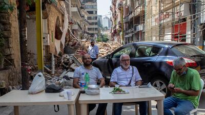 Lebanese citizens take breakfast next to an older building with damages from the Beirut port explosion, at the Gemayzeh street in Beirut, Lebanon. EPA