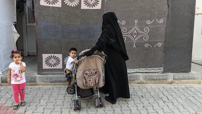 A Syrian woman stands with her children in front of her home. Getty Images