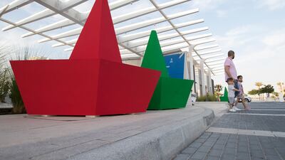 Visitors pose in front of the origami-style boats.