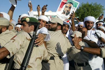Emirati policemen control the crowd during the funeral of Sheikh Zayed bin Sultan al-Nahayan (seen in portrait) in Abu Dhabi 03 November 2004. Nahayan, the president and founding father of the United Arab Emirates, died 02 November 2004 after more than 30 years at the helm of his oil-rich country. AFP PHOTO/RABIH MOGHRABI / AFP PHOTO / RABIH MOGHRABI