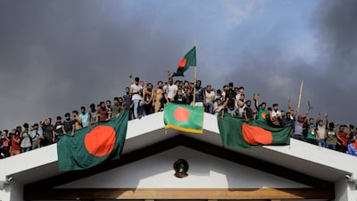 Protesters display Bangladesh's national flag as they storm Prime Minister Sheikh Hasina's palace in Dhaka. Army chief Waker-Uz-Zaman said he was ‘taking full responsibility’ of Bangladesh after the PM was ousted and fled the country. AFP