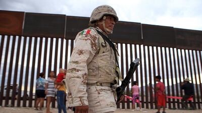 A Mexican soldier walks in front of families on the US-Mexico border. AFP