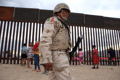 A Mexican soldier walks in front of families on the US-Mexico border. AFP