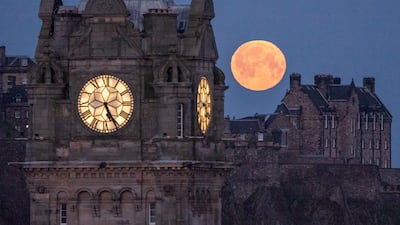 The pink moon sets behind the Balmoral Clock and Edinburgh Castle on Wednesday. PA