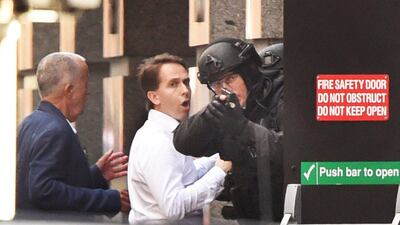 Two hostages run for cover behind a policeman during a hostage siege in the central business district of Sydney on December 15, 2014. William West / AFP Photo