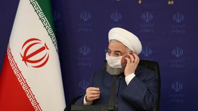 Iran's President Hassan Rouhani adjusts his face mask in a meeting amid the fight against the Covid 19 pandemic, in Tehran, Iran. AP