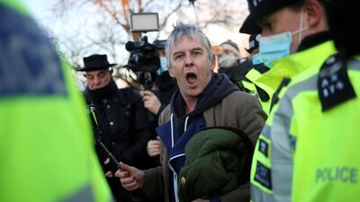 An anti-lockdown protester is escorted away by police, as people gather at a memorial site at Clapham Common bandstand, London. Reuters