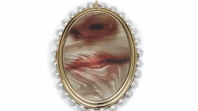 Lips are the focus of this oversized pendant, strung on a chain speckled with pearls