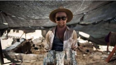 Excavation volunteer Joshua Talbot displays the remains of a sphinx with a hieroglyphic inscription between its paws, found during excavation works in the archeological site of the ancient Tel Hazor.