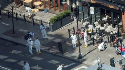 Evidence technicians work at the site of one of the bombings on Boylston Street as an investigation continues into the bombings near the finish line of the Boston Marathon.