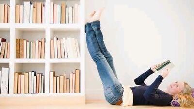 Young woman reading next to bookshelf