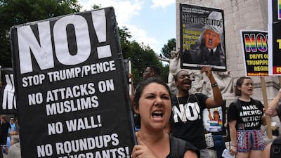 Protesters hoist signs at Columbus Circle in New York City prior to a march to Trump Tower to denounce the Supreme Court's reinstatement of large parts of the Trump/Pence travel ban. Timothy Clary / AFP