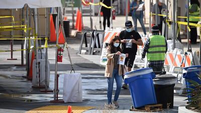People drop their self-administered coronavirus test sample into a collection bucket at a Covid-19 testing site in a park in Los Angeles, California, a few days ahead of the Thanksgiving holiday. AFP