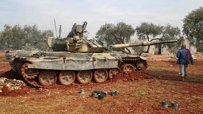 A Syrian rebel fighter walks by a tank in Syria's northern Idlib countryside amid clashes with government forces. AFP