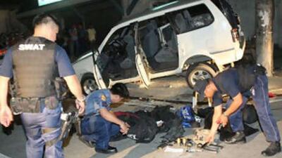 Police investigators check the weapons and ammunitions and other items allegedly used by suspected robbery gang members after they were killed in a shootout.
