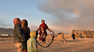 Internally-displaced Afghan children watch a girl jump with a skipping rope at a refugee camp in Ghazni. Saued Zakeria / AFP Photo