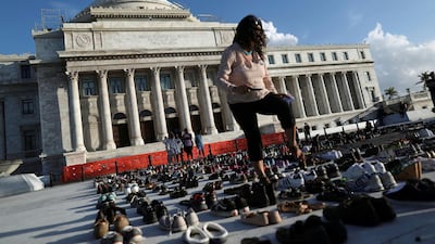 A woman walks among hundreds of pairs of shoes displayed at the Capitol to pay tribute to Hurricane Maria's victims in San Juan, Puerto Rico. Alvin Baez / Reuters