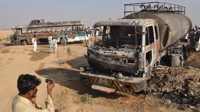 People and rescue workers inspect the wreckage of a bus after it collided with an oil tanker and burst into flames, near Karachi. Shahzaib Akber / EPA