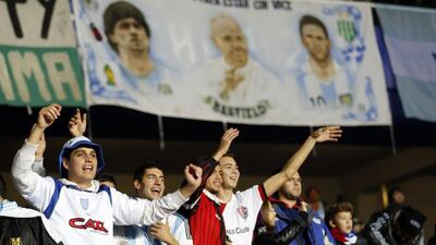 Argentina fans cheer on their team under a banner depicting Diego Maradona, Pop Francis and Lionel Messi during the Copa America semi-final on Tuesday night. Silvia Izquierdo / AP