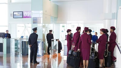 Qatar airways pilots and cabin staff wait at an airport departure gate before boarding a flight. Loop Images / UIG via Getty Images