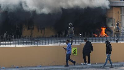 Members of Iraqi security forces stand guard near burning tyres at the reception room of the embassy. Reuters