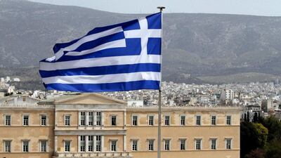 A Greek flag flies from the roof of a building as the house of Parliament is seen in the background in central Athens. Dimitri Messinis / AP Photo