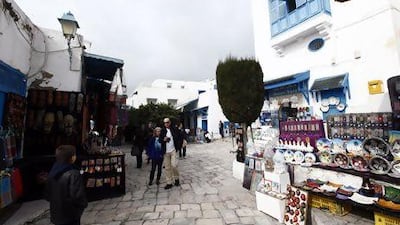 Tourists walk past the traditional souvenirs displayed for sale in Sidi Bou Said, a town that can be reached easily and cheaply from Tunis, and one which is a draw for city dwellers and foreign bargain hunters alike. Reuters / Anis Mili