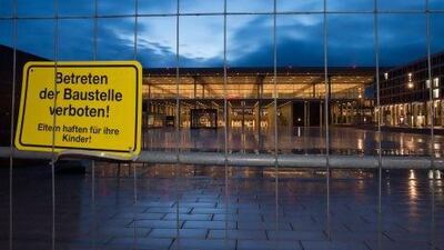 The new Berlin Brandenburg airport Willy Brandt (BER) behind a construction site fence with a warning sign, in Schoenefeld. Earmarked to open in 2011, it is unlikely to open until 2015 or later.