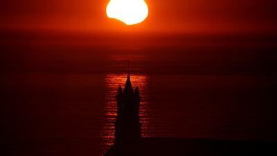 The Saint-They Chapel is seen in silhouette at sunset during a partial solar eclipse, as the moon passes in front of the sun, seen at the Pointe du Van, in Brittany, France. Mal Langsdon / Reuters