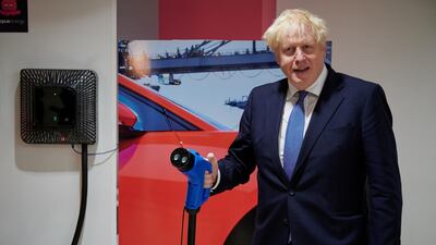 Britain's Prime Minister Boris Johnson holds an electric vehicle charging cable as he visits the headquarters of Octopus Energy, in London, Britain October 5, 2020. Leon Neal/Pool via REUTERS