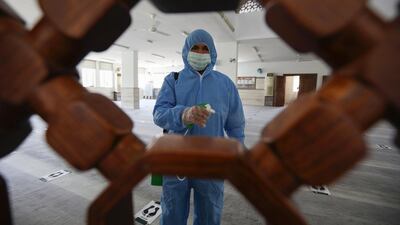 A worker wears a protective suit while spraying disinfectant in a mosque in Amman, Jordan. REUTERS