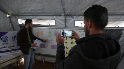 A man films a maths lesson by teacher Ahmed Rateb inside a tent, in a camp for displaced Syrians in the village of Kafr Yahmoul in the northwestern Idlib province. AFP