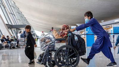 A child flown from Kabul pushes a wheelchair with a woman at Washington Dulles International Airport, in Chantilly, Virginia. AP