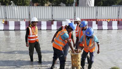 Workers at the under construction Dubai Metro site clear the rain water at a street in Discovery Gardens. Pawan Singh / The National