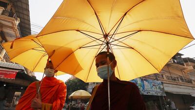 Buddhist monks wear face masks as they receive alms from devotees in Phnom Penh, Cambodia. AP Photo