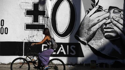 A woman rides her bicycle past a graffiti mocking the Brazilian currency note, the real, in downtown Rio de Janeiro. Pilar Olivares / Reuters
