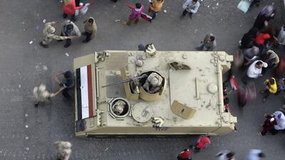 Egyptians walk around an armoured personnel carrier parked at a pro-military rally marking the third anniversary of the 2011 uprising in Tahrir Square in Cairo, Egypt, on January 25, 2014. Amr Nabil / AP Photo