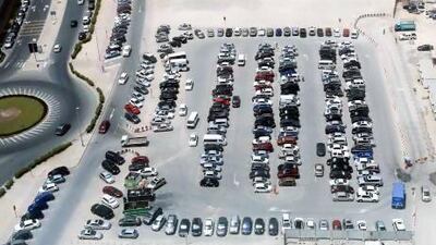 Drivers circle Dubai Media City's only public parking lot in search of a space, while vacant land to the left and right remains cordoned off as "a matter of public safety". Sarah Dea / The National