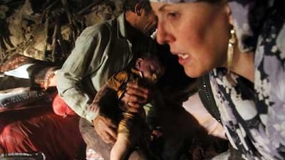 An Iranian man carries the body of a child after finding it in the rubble of a house in Sourmah village, near the town of Varzaqan.