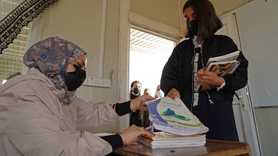 Girls receive text books before heading to class on the first day of school at a Yazidi displacement camp in the Sharya area near the city of Dohuk in Iraqi Kurdistan. AFP