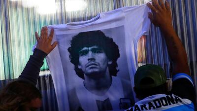 Fans hold a jersey with the face of Diego Maradona at Clínica Olivos. Getty Images