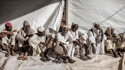 Men who have fled the war in Sudan line up during a cash assistance programme at the transit centre