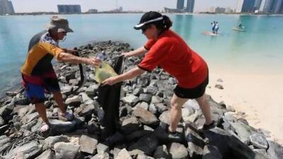 Wayne Young and Mary Vedra from Paddlers for the Planet help to clean up the beach at the Abu Dhabi Sailing and Yacht Club. Sarah Dea/The National