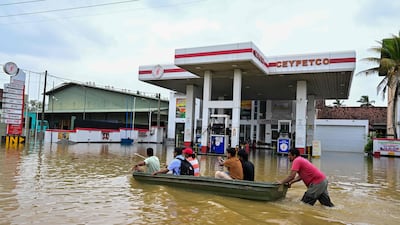 People ride a boat across a flooded street in Ambatale. AFP