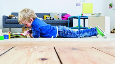 Boy playing with digital tablet on wooden floor. Getty Images